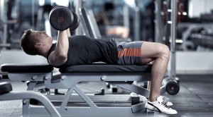 Young man doing a chest and arms workout with a dumbbell bench press exercise