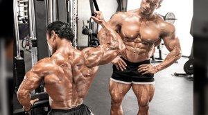 Bodybuilding partners and spotter doing a back workout with a single arm lat pulldown exercise