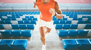 Physically fit man doing a cardio HIIT workout by running up a flight of stairs