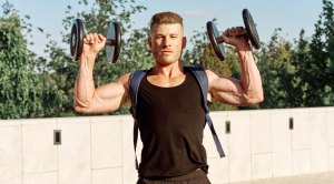 Muscular-Man-wearing-backpack-and-carrying-dumbbells-outside