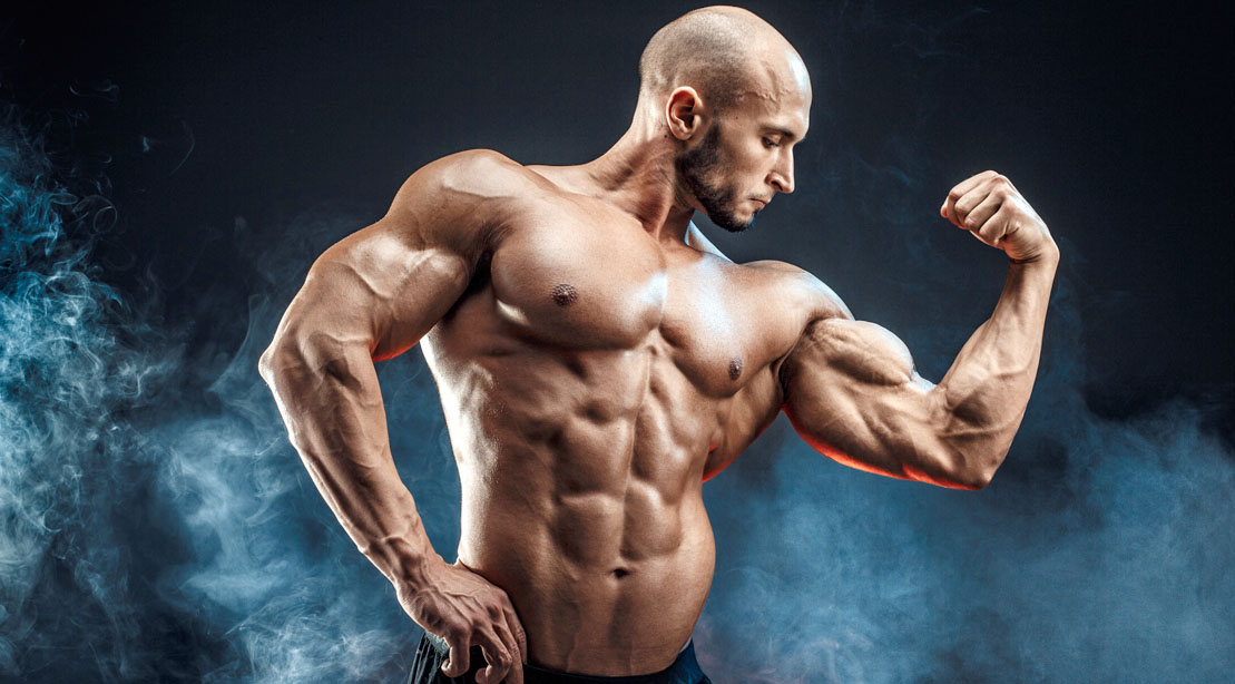 Bald muscular bodybuilder with big biceps muscle after following accessory training methods