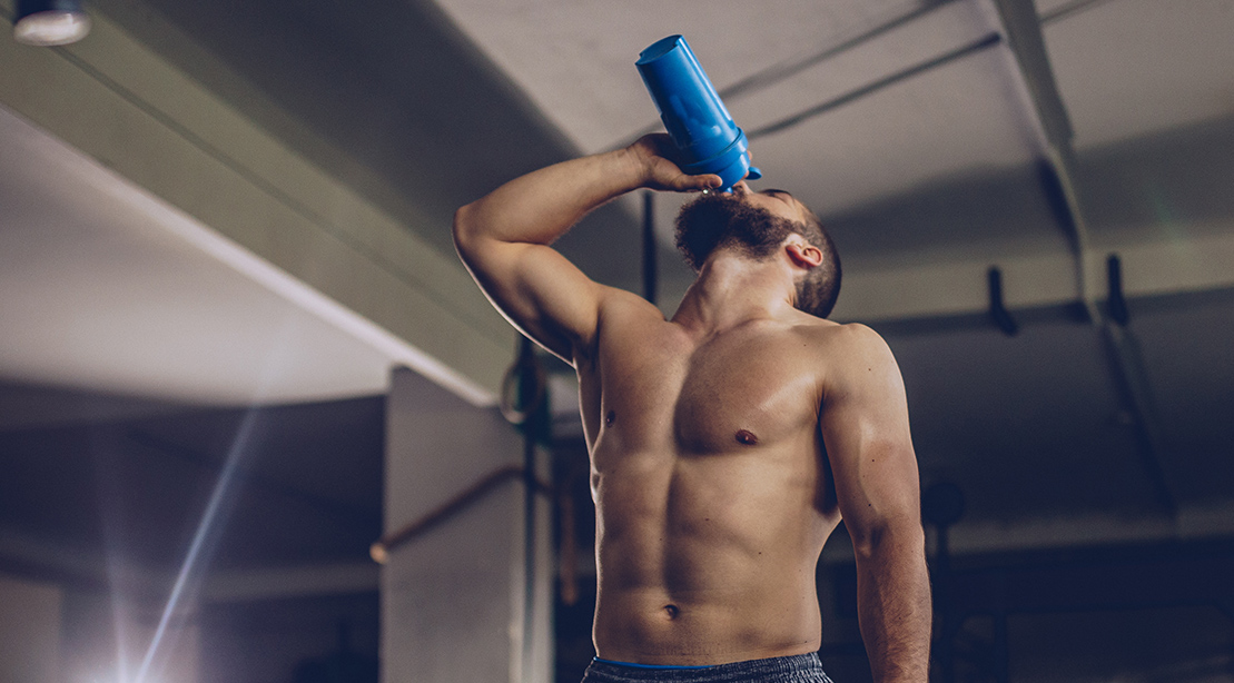 Muscular and fit man drinking a protein shake and drinking a post workout supplement