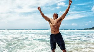 Man with abs celebrating in the ocean