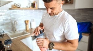 Man preparing a supplement protein shake in his kitchen