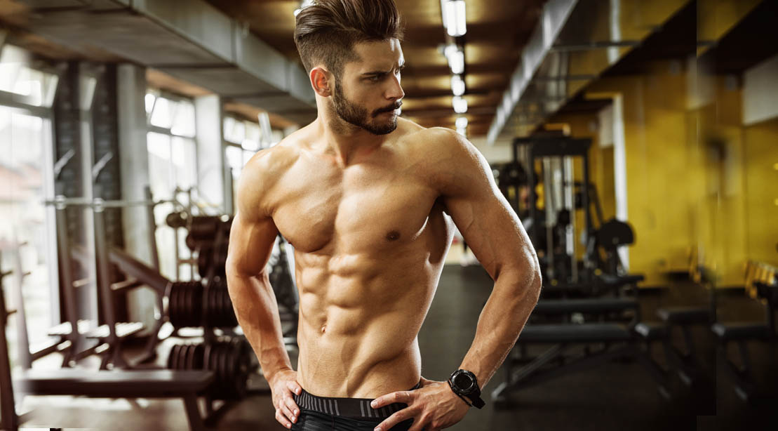 Muscular man with ab muscles standing in a gym after doing abs exercises