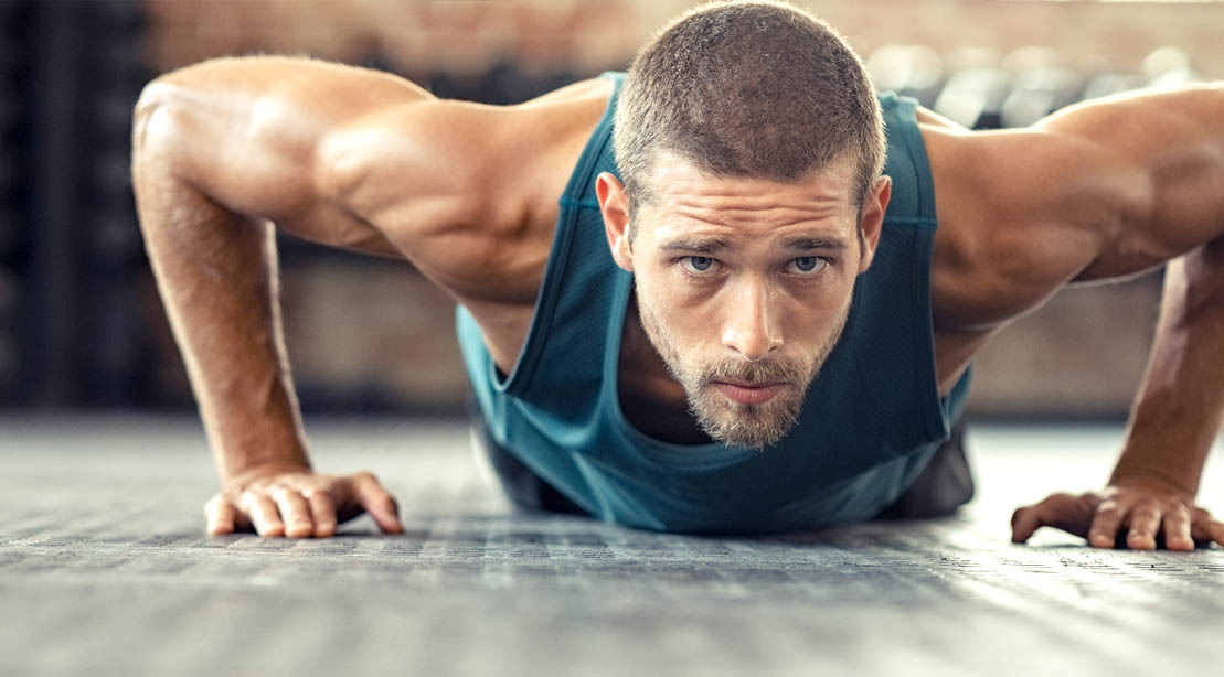 Fit man with a beard doing a bodyweight workout and doing a half rep pushup exercise