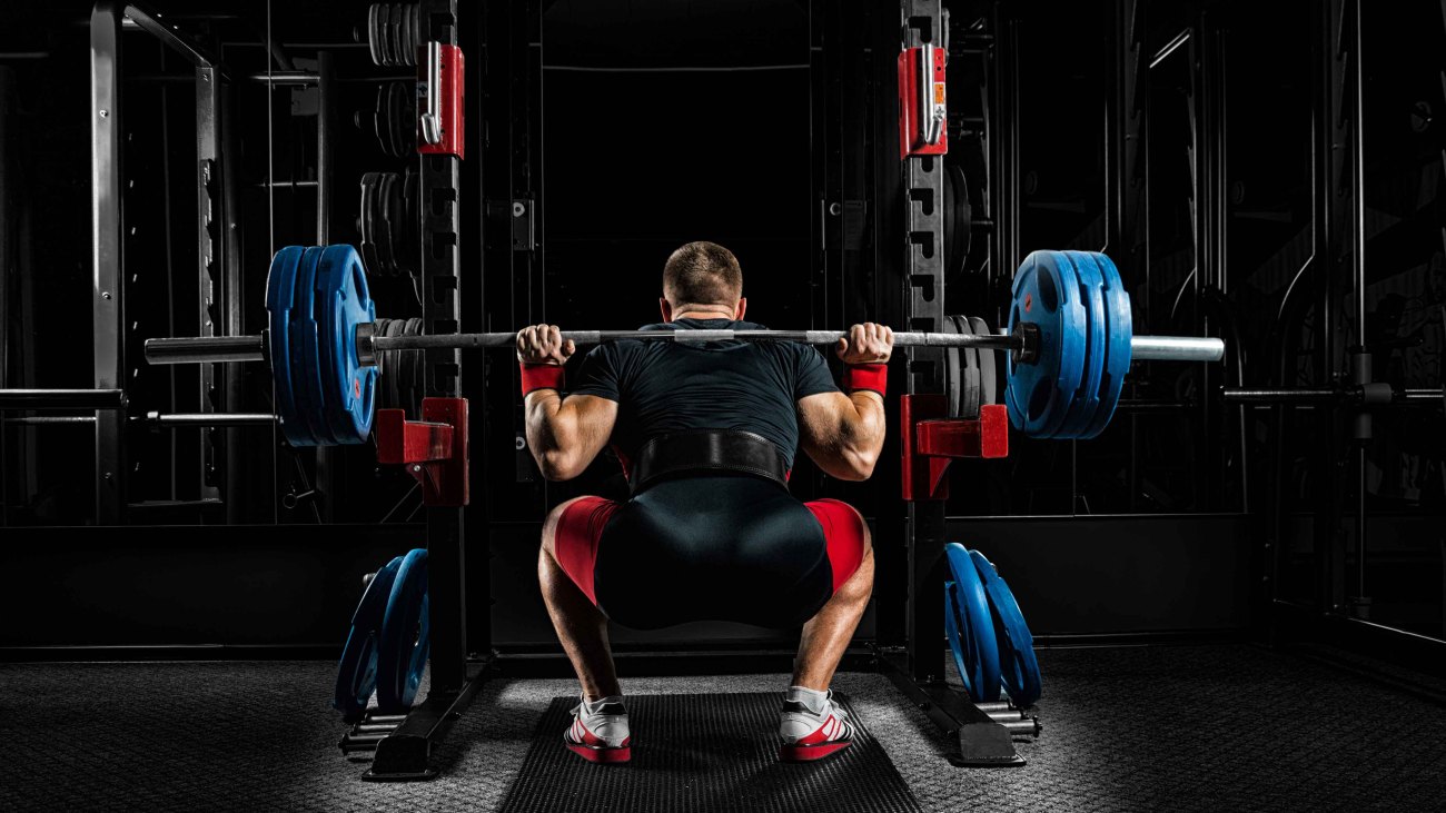 Power lifter at a squat rack doing a barbell back squat