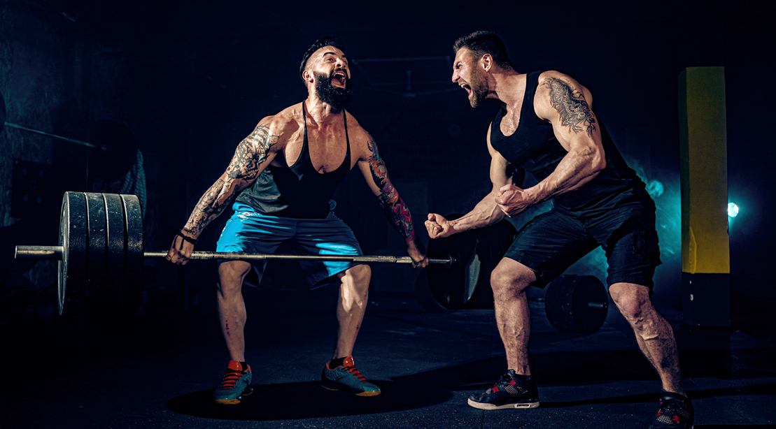 Muscular-Man-Deadlifting-Heavy-Weights-Struggling-workout-Partner motivating partner to get over his fitness plateau using the progressive overload method