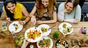 Three-Girls-Sitting-At-Restaurant-Eating-Healthy