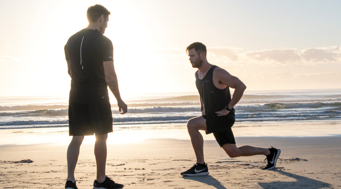 Chris-Hemsworth-Training-With-Luke-Zocchi-Lunges-On-Beach-Sunrise