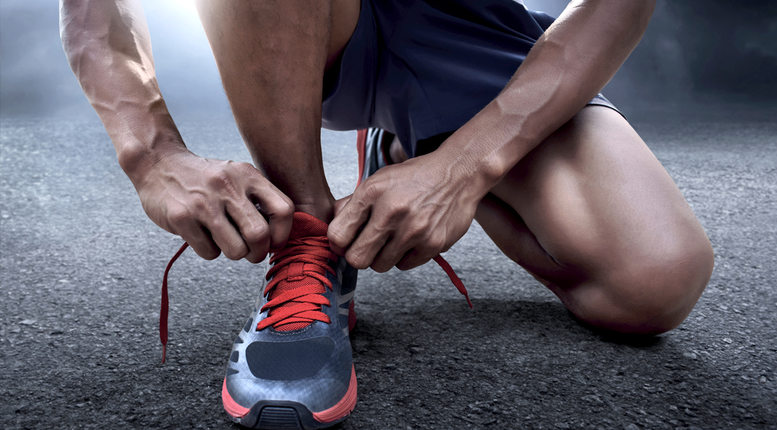 Male runner tying his running shoes in preparation for running a marathon