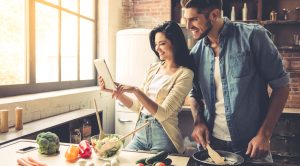 Couple-Learning-To-Cook-In-Kitchen-Lookiing-At-Ipad