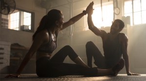 Fit-Couple-High-Fiving-In-Dark-Gym