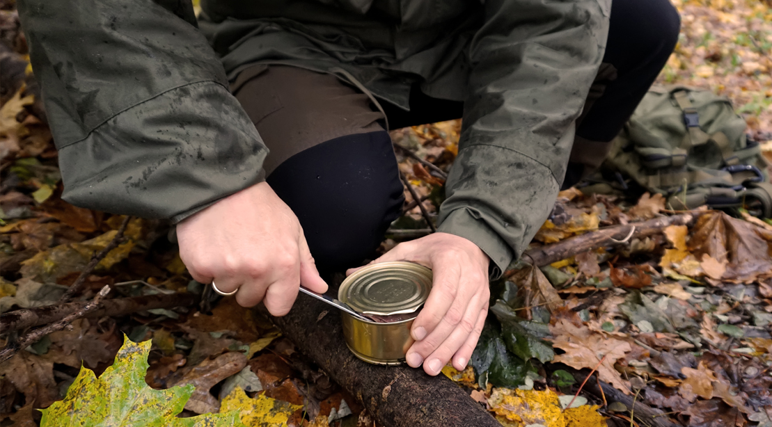 Survival-Camper-Opening-Can-Food-With-Pocket-Knife