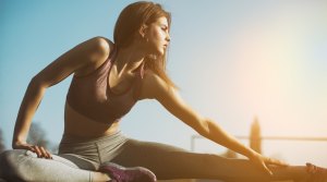 Young-Fitness-Female-Stretching-Legs-In-Sunset