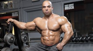 IFBB Pro-bodybuilder Jon DeLarosa in the gym standing next to a barbell rack