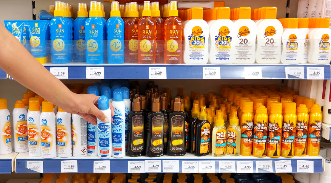 Person shopping for sunscreen in the sunscreen aisle of the supermarket