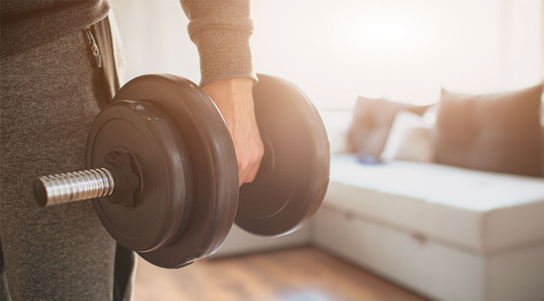Beginner trainer working out with a dumbbell at home using the beginner training guide