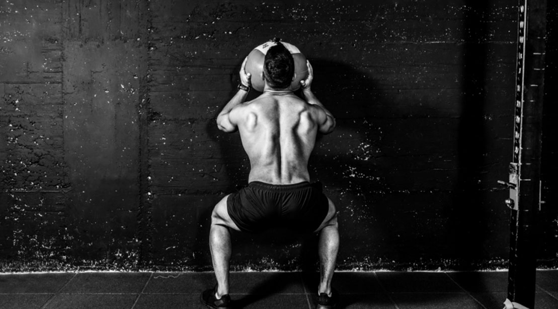 Bodybuilder with a muscular back working out with a medicine ball