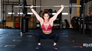 Kelly Stone performing an Olympic lift with a barbell in the gym