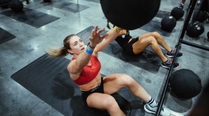 Fit white female performing a medicine ball situp throw for the Deka workout