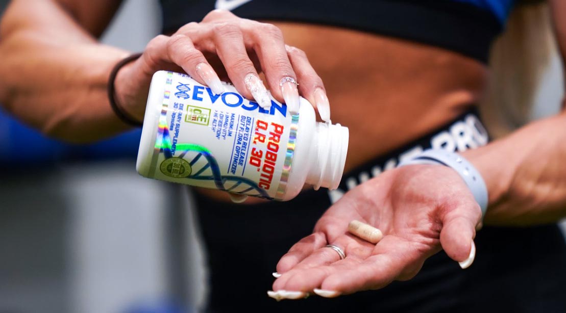 Female bodybuilder taking the Evogen Nutrition Probiotic D.R. 30 supplement pill