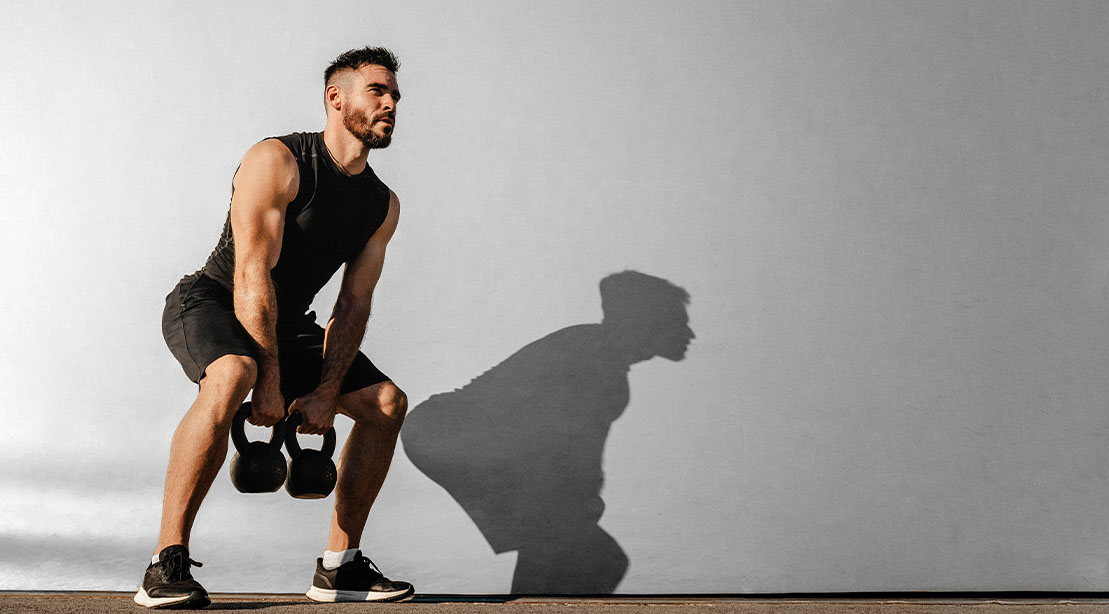 Muscular man performing a bodybuilding kettlebell workout