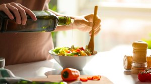 Woman pouring olive oil into a bowl of salad