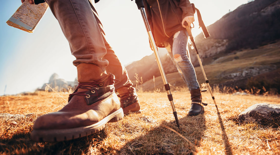 Couple legs hiking with hiking boots, hiking poles, and 2023 hiking gear for men
