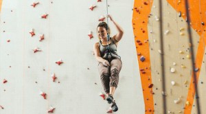 Woman coming down from a indoor rock climbing facade while strapped to a harness