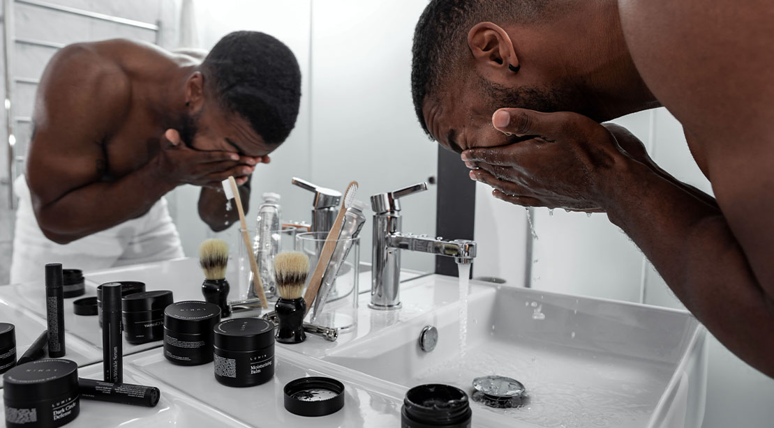 Muscular man washing his face for skin care